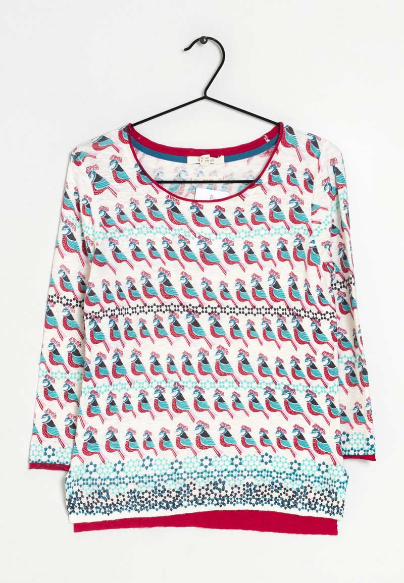 Langearmige top met een ronde hals, versierd met een herhalend vogelpatroon in rood, blauw en crème, met een contrasterende zoom in donkerroze.