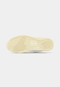 Zool van off-white sneaker met een textuur zigzagpatroon en rechthoekig Tommy Jeans-logo dicht bij het booggebied.