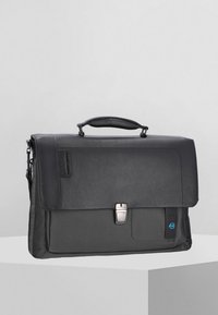 Attività in pelle nera e tessuto con un lembo, chiusura argentata e tracolla staccabile. Presenta una finitura texturizzata e un accento blu.