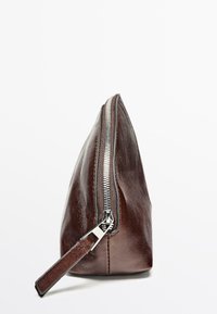 Brun læderpung med metallynlås, konisk design og glat tekstur. Inkluderer en læderlynlås træk. Sidevisning vist mod en hvid baggrund.