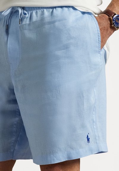 Light blue linen shorts with an elastic waistband and drawstring. Features a small embroidered logo on the lower hem. Smooth texture.