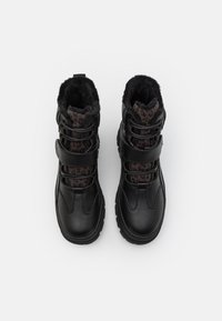 Bottes d'hiver noires avec une doublure en fausse fourrure et des accents imprimés léopard, équipées de lacets et de sangles réglables pour un ajustement sécurisé.