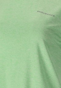 Tissu texturé vert clair avec de petites perforations et le mot « ENDURANCE » imprimé en gris foncé près du coin supérieur droit.