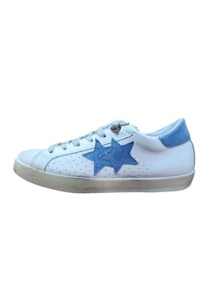 Sneaker bianca basse con toppe a forma di stella in denim azzurro chiaro sul lato, linguetta del tallone blu, lacci bianchi e suola leggermente consumata.