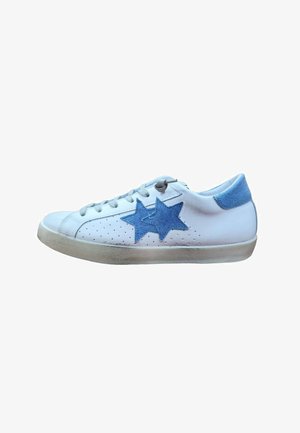 Sneaker bianca basse con toppe a forma di stella in denim azzurro chiaro sul lato, linguetta del tallone blu, lacci bianchi e suola leggermente consumata.
