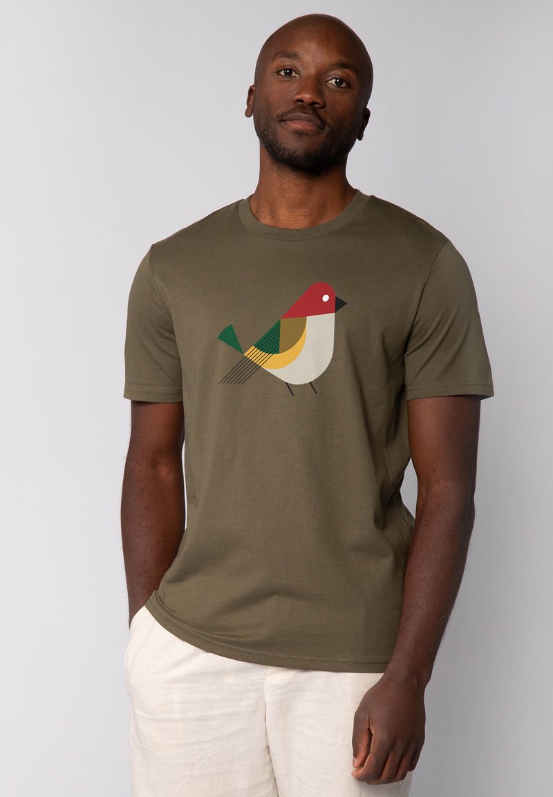 T-shirt en coton vert olive arborant un graphique stylisé d'oiseau en rouge, jaune, vert et noir. Manches courtes et col rond.