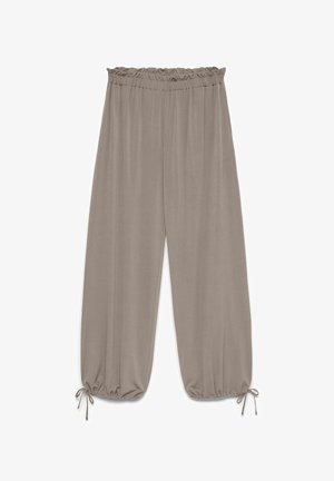 Pantalon taupe ample avec taille élastique et chevilles froncées attachées par de fines lanières en tissu.
