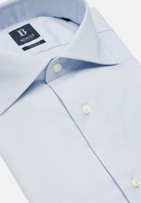 Ljusblå skjorta med knappar i en slät tyg. Har en klassisk krage och vita knappar, med en etikett synlig inuti.