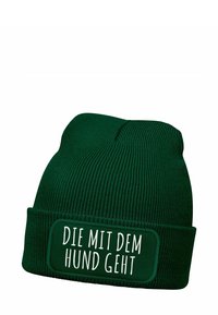 Green knitted beanie featuring a contrasting stitched patch with white text "DIE MIT DEM HUND GEHT," ribbed texture, and folded cuff design.