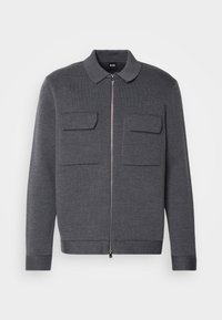 Šedá bunda na zip s límcem, dvěma předními kapsami, žebrovanou texturou a manžetami. Minimalistický design bez viditelných vzorů nebo kovových doplňků.