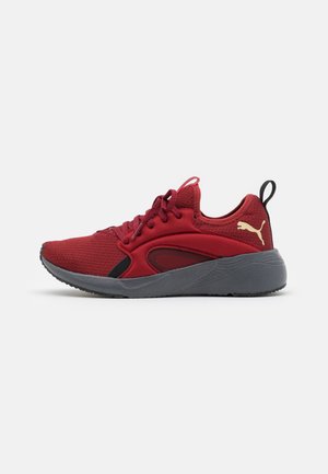 Red athletic shoes with a textured upper, black accents, and a grey sole. Features laces and a Puma logo in gold on the heel.