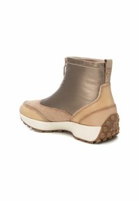 Botín marrón hasta el tobillo con un acabado suave y texturizado. Presenta una base de color beige claro, suela de goma y un cierre con cremallera para ponerlo y quitarlo fácilmente. Decorado con logotipos sutiles.