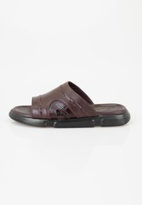 Bruine leren slippersandalen met een brede band en textuurdetails, voorzien van een rubberen zool voor grip en comfort.