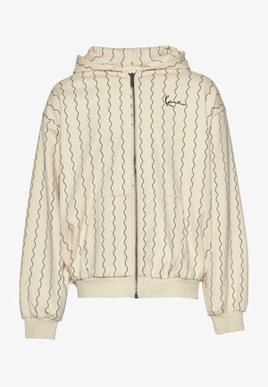 Gai bēšs kapuce ar viļņveidīgām melnām līnijām, pilna zipa, kangru kabata un ribota piedurkne. Mīksts audums ar brīvu piegriezumu un kapuci.