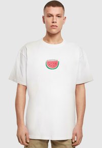 Hvid bomuld t-shirt med korte ærmer, der viser et vandmelon grafik og teksten "summertime" i et afslappet skrifttype. Løs pasform.