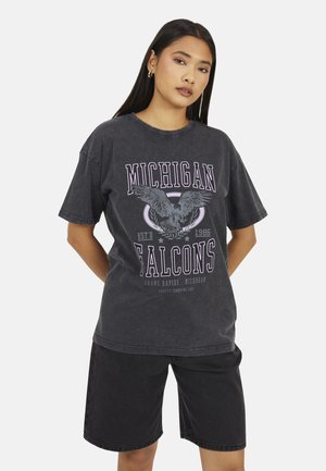 Gray oversized t-shirt with a Michigan Falcons graphic, featuring an eagle design and established date, paired with black denim shorts.