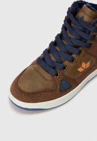 Sapatilha alta castanha com atacadores azul-marinho, apresentando um cabedal texturizado e um detalhe azul escuro. Inclui um logótipo laranja na lateral.