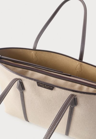 Μπεζ τσάντα ώμου από καμβά με καφέ δερμάτινες λαβές και λεπτομέρειες, χρυσό φερμουάρ και το λογότυπο «Tory Burch New York» στο μπροστινό μέρος.