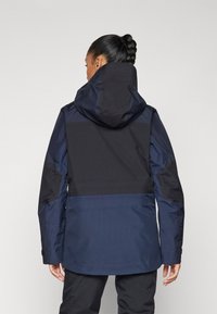Wasserfeste Jacke in Marineblau und Schwarz, mit Kapuze, verstellbaren Bündchen und einer glatten, strukturierten Oberfläche im Farbblockdesign.