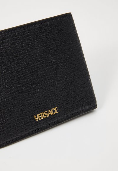 Black leather wallet with a textured finish and gold "VERSACE" logo. Features a sleek rectangular shape with stitched edges.