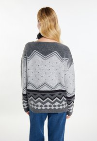Grau gestrickter Pullover mit geometrischen Mustern, einschließlich Zickzacklinien und Punkten, mit lockerem Schnitt und weitem Ausschnitt. Weiche Textur.