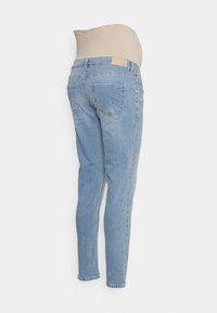 Jeans de maternidade azul claro com uma cintura elástica bege, design de cinco bolsos, pernas ajustadas e textura de denim desbotada.