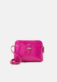 Różowa torebka na ramię z imitacji skóry krokodyla, z zamkiem błyskawicznym, płaskim paskiem i małym ozdobnym chwostem. Złote elementy ozdobne.