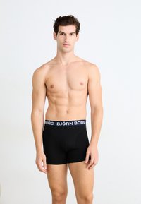 Schwarze Boxershorts mit einem logo-eingearbeiteten Bund. Gefertigt aus einem glatten Stoff, mit einer taillierten Passform und kurzen Beinen. Keine sichtbaren Muster oder Akzente.