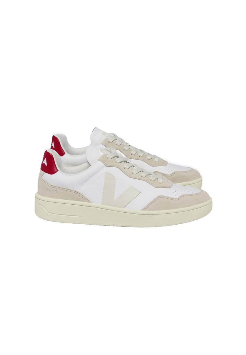 Baskets blanches avec un capuchon en daim beige et des panneaux latéraux. Accents rouges sur le talon et le logo, avec un système de laçage. Texture douce.