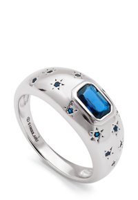 Anillo de plata con una gema azul rectangular en el centro y pequeñas piedras azules en forma de estrella grabadas alrededor de la banda.