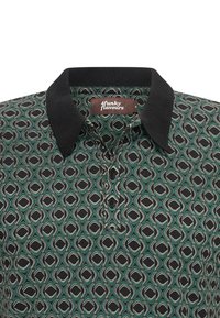Camisa de cuello con patrón geométrico de diamantes en verde, negro y blanco, y cuello acanalado negro, con tres botones negros en la tapeta.