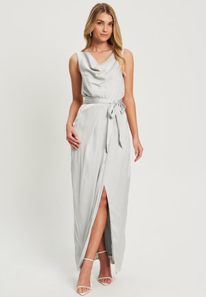 Long, light grey dress with a cowl neckline, cinched waist featuring a tie, and a thigh-high slit. Smooth, satin-like fabric with elegant draping.