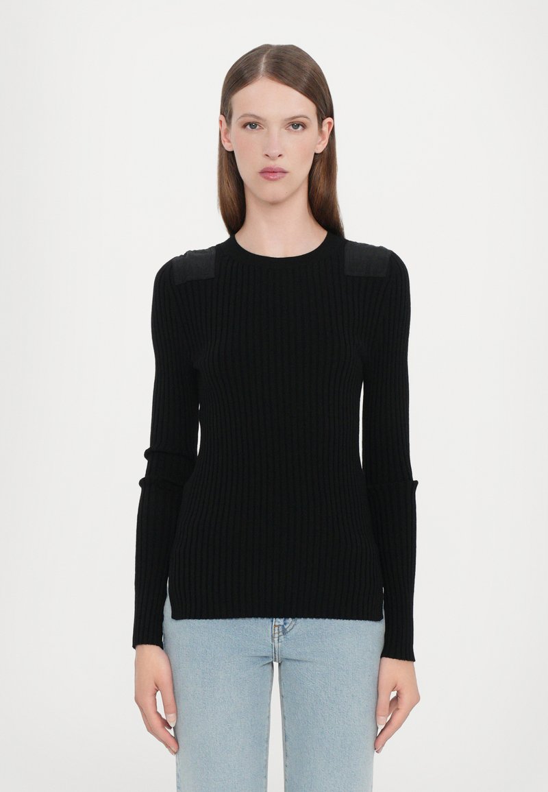 Black ribbed sweater featuring a fitted design, long sleeves, and subtle shoulder accents. Paired with light blue denim jeans.
