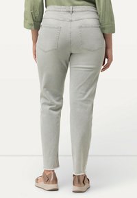 Grijze denim broek met hoge taille, rechte snit, twee achterzakken en een rauwe zoom. Draag met bruine platform sandalen.