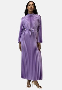 Lilla plisseret maxikjole med høj halsudskæring, lange ærmer og bundet talje. Har et tekstureret stof og subtil farvegradient.