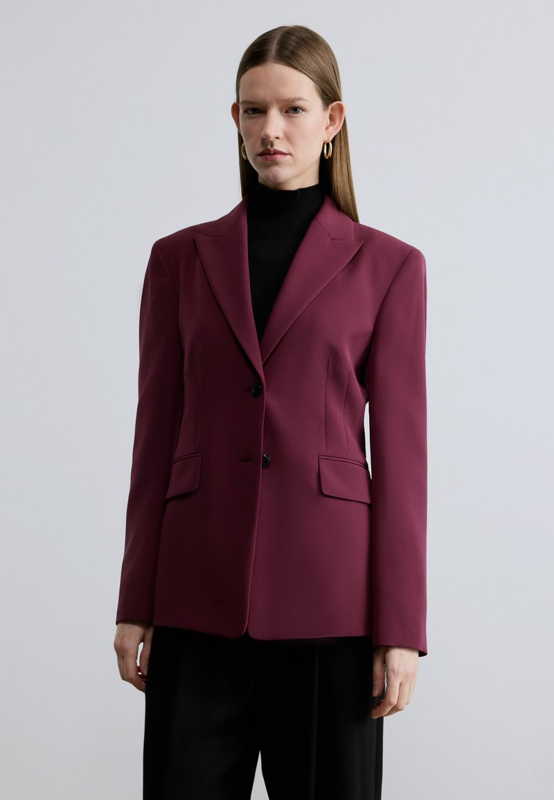 Bordeauxrode blazer met een getailleerde pasvorm, twee voorzakken en een sluiting met één knoop. Gladde stof, revers met inkeping en een gestructureerd schouderontwerp.