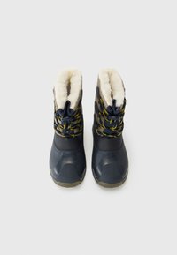 Par de botas de invierno en navy y beige con cordones acentuados en amarillo y forro de felpa blanca, vistas desde arriba sobre un fondo blanco.