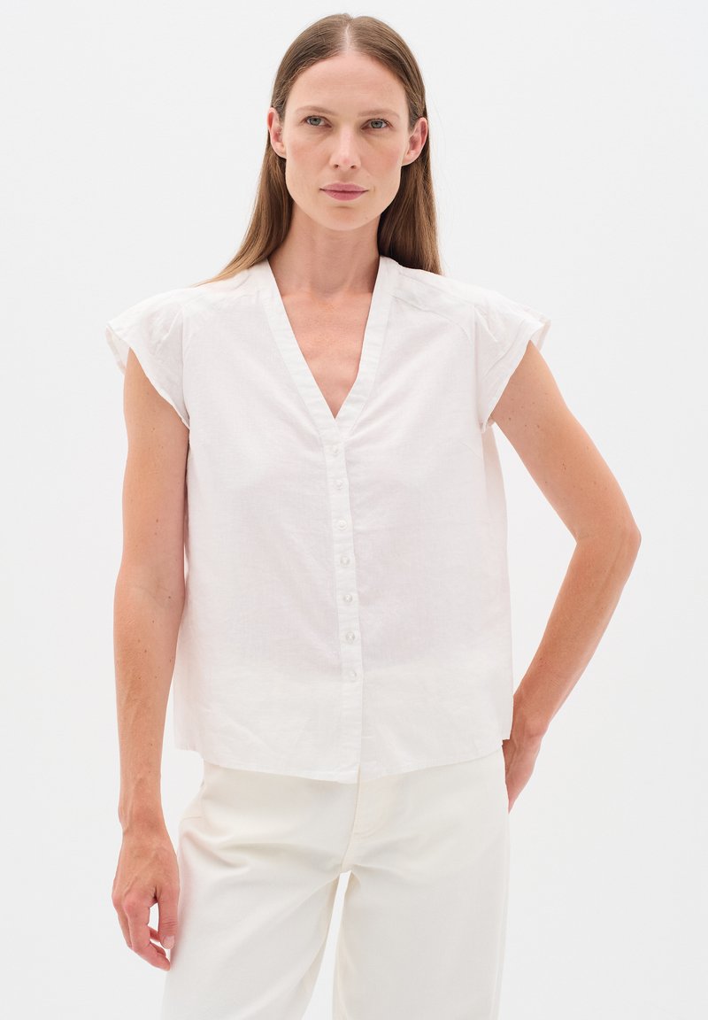 White linen short-sleeve shirt with a V-neck and button-down front, featuring soft texture and a relaxed, loose fit.
