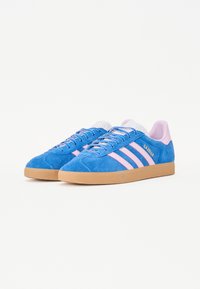 Sneaker blu scamosciati con strisce rosa, punta arrotondata, suola in gomma e lacci a fantasia. Marchio visibile sul lato in oro.