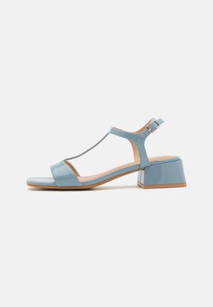 Jasnoniebieska sandałka z lakierowanej skóry z paskiem w kształcie litery T, klockowym obcasem, odkrytymi palcami i regulowaną klamrą przy kostce. Gładka tekstura i minimalne zdobienia.