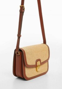 Ruskea nahkainen olkalaukku, jossa on kudottu olkipinta, kultasulkija ja säädettävä hihna. Kompakti suorakulmainen muoto, jossa on siistit ompeleet.