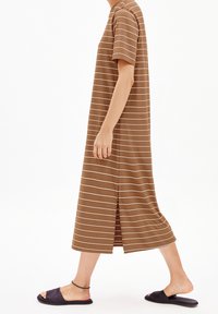 Hnědé maxi šaty s pásky, krátkými rukávy, volným střihem, rozparkem na boku a hladkou texturou. Nošené s černými nazouváky.