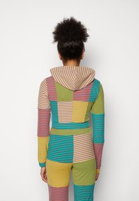 Survêtement à capuche coloré en tissu rayé et patchwork. Comprend plusieurs couleurs, dont le vert, le jaune, le rose et le bleu.