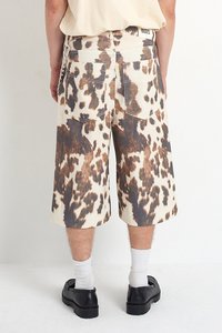 Beige shorts med et mønster av brune og svarte leopardflekker, med baklommer og beltestropper, laget av denimstoff.
