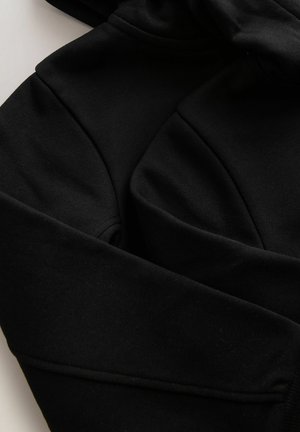 Must kapuutsiga dressipluus pehmest kangast, sileda tekstuuriga. Omadustega kängurutasku ja soonikkoes mansetid, esitledes lõdvestunud disaini ja sobivust.