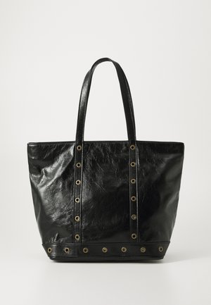 Black leather tote bag with two handles and gold metal eyelet details along straps and bottom edge against white background.