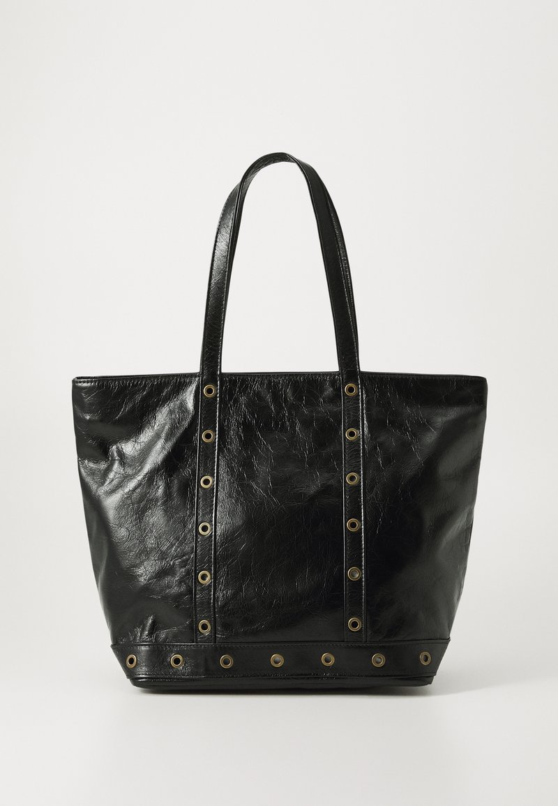 Sac fourre-tout en cuir noir avec deux poignées et détails en œillets en métal doré le long des sangles et du bord inférieur sur fond blanc.