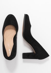 Svarta mocka högklackade skor med rund tå och blockklack. Innersulan har små ventilationshål för ökad komfort.