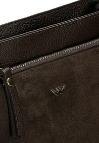 Clutch in suede marrone con rifiniture in pelle testurizzata, dotato di una cerniera argentata e di un accento metallico con logo. Design semplice e sofisticato.