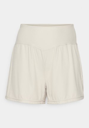 Shorts beige clair avec une taille côtelée texturée, un design fluide et une coupe décontractée. Comporte des ourlets cousus et des fentes latérales pour plus de flexibilité.